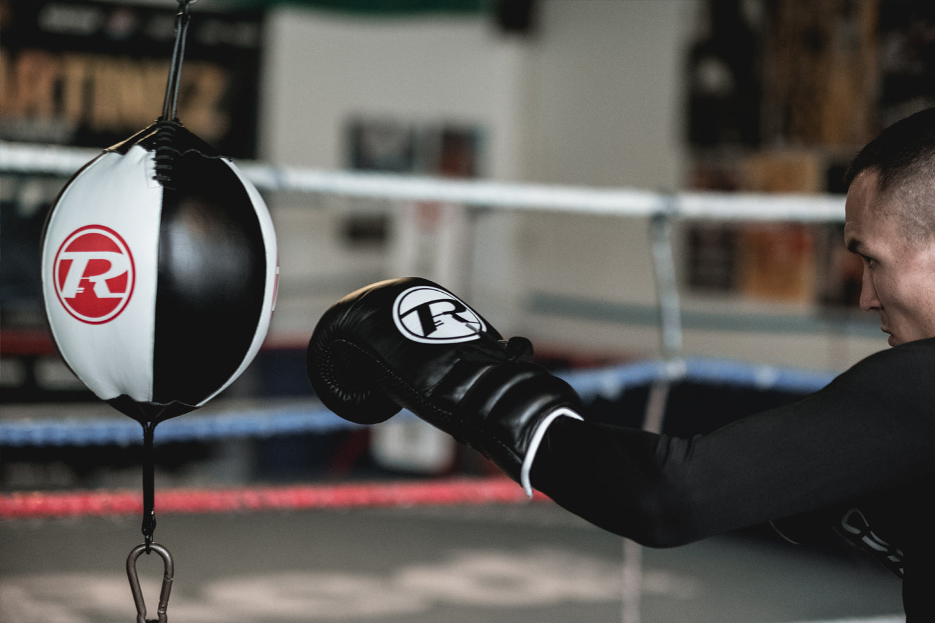 Boxer wearing black boxing gloves punching floor to ceiling ball